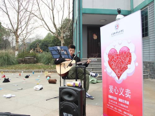 图二 义卖现场,志愿者献唱拉动人气.JPG
