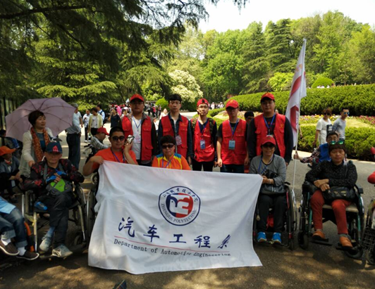 图二,志愿者们冒着炎热给残疾人士推轮椅.png